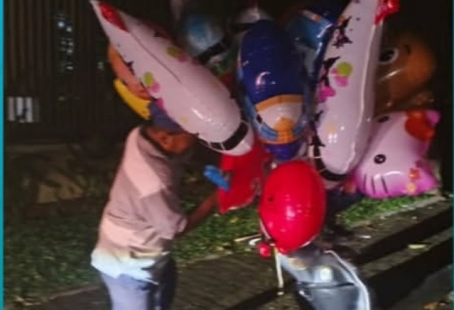 Pedagang balon kembali mengikat balonnya di motor setelah berhasil dievakuasi petugas Damkar. [Instagram]